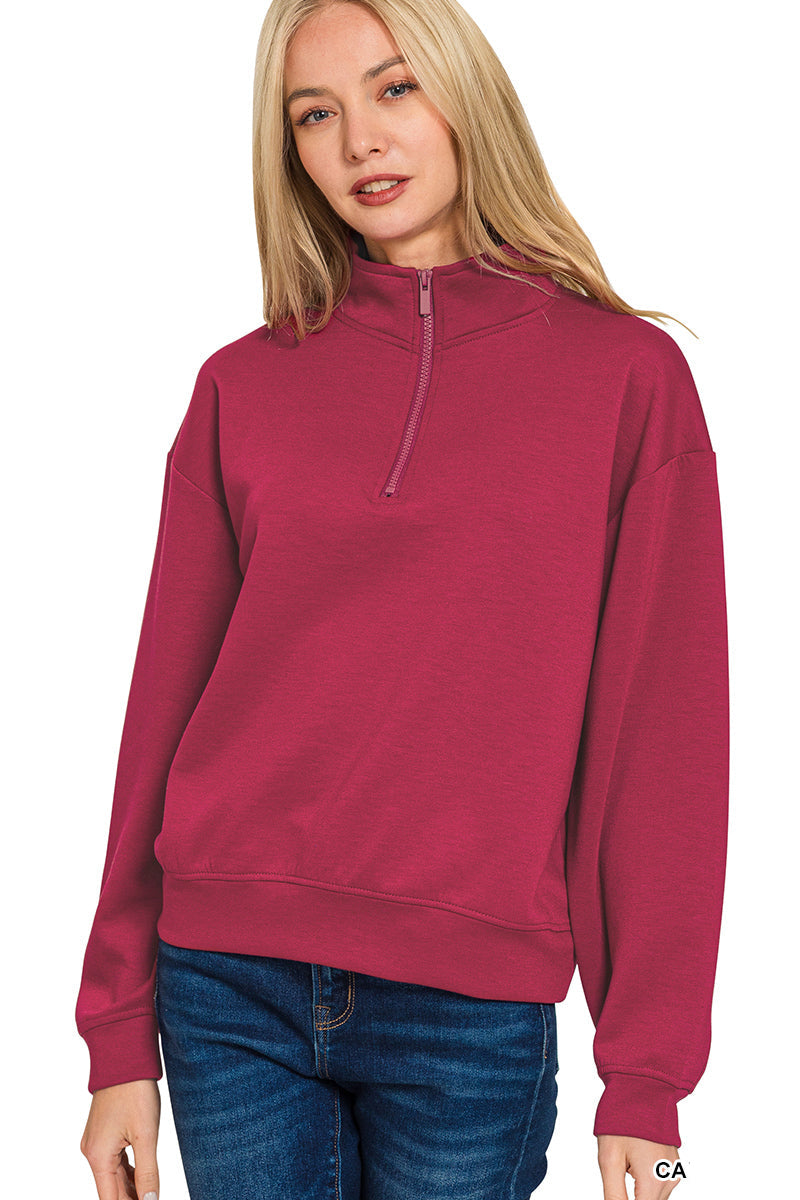 Woman wearing a maroon half-zip sweatshirt on a white background