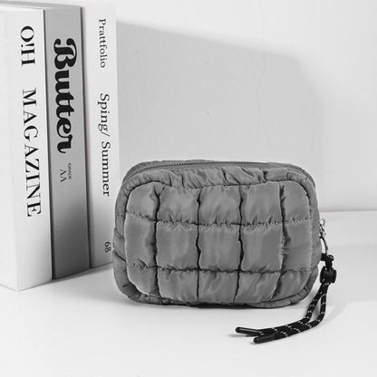 Ash grey quilted pouch on a white surface with a magazine in the background