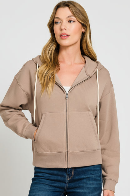 Woman wearing a beige hoodie with a white background