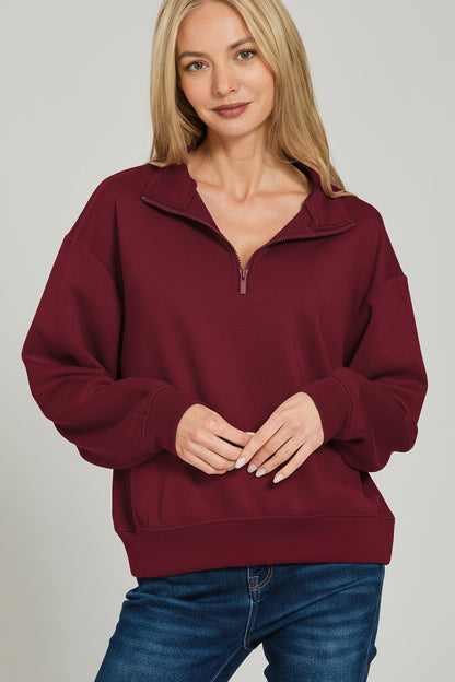 Woman wearing a magenta pullover with a quarter zip on a white background
