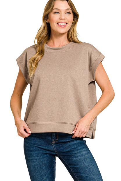 Woman wearing a beige sleeveless top and blue jeans on a white background